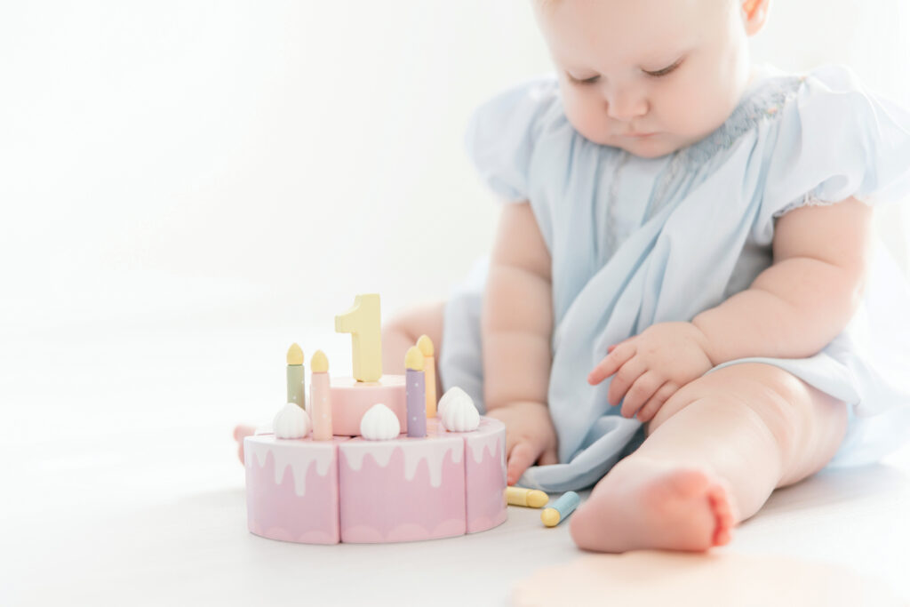 Close up of baby with first birthday cake wooden toy
