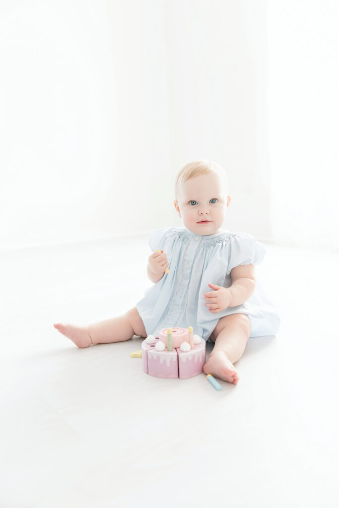 First birthday portrait of a baby girl sitting on light wood flooring