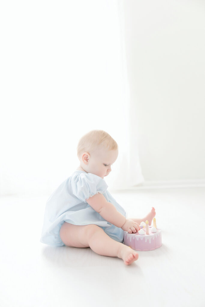 Baby girl playing with wooden birthday cake toy during Savannah ga photo session.